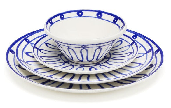 A set of blue and white ceramic dinnerware from Themis Z Kyma Blue Collection, including a bowl, a dessert plate, a salad plate, and a dinner plate, stacked on top of each other. The intricate line patterns evoke summer memories by the Greek Aegean sea.