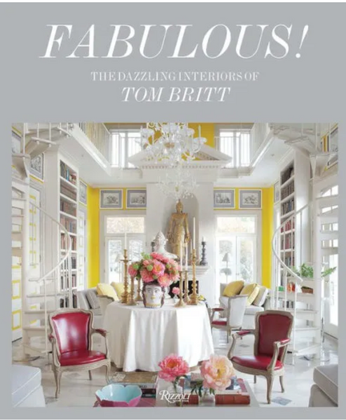 A book cover titled "**Fabulous!: The Dazzling Interiors of Tom Britt**" showcases an elegant and colorful living room with a central table, vibrant chairs, and elaborate decorations, epitomizing masterful design. Published by **Rizzoli**.