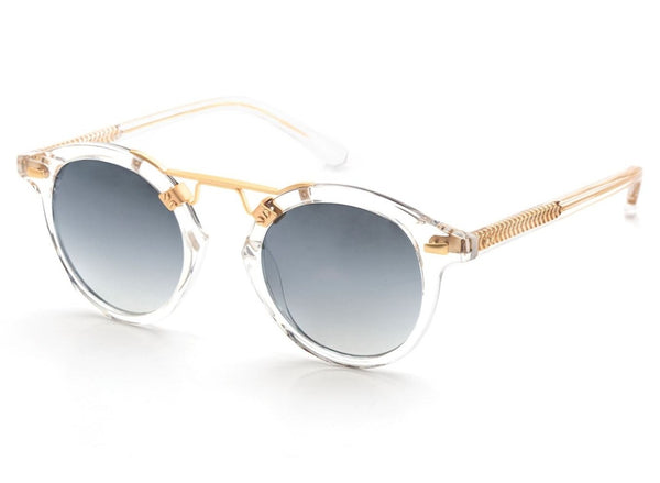 A pair of Krewe St Louis Mirrored Sunglasses by Krewe, featuring luxury acetate clear frames, 24K gold-plated accents, and gradient dark lenses that offer complete UVA/UVB protection.