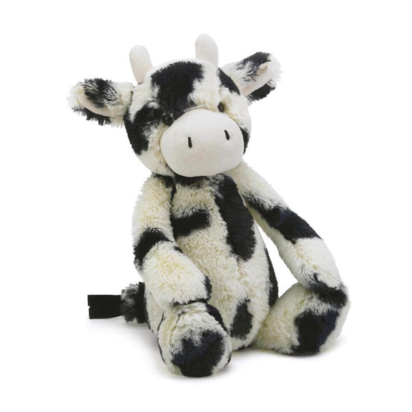 A plush toy in the shape of a black and white cow with super soft spotted fur, a friendly expression, and a fluffy texture, perfect for a cuddle buddy. Introducing the Jellycat Bashful Calf, Medium!