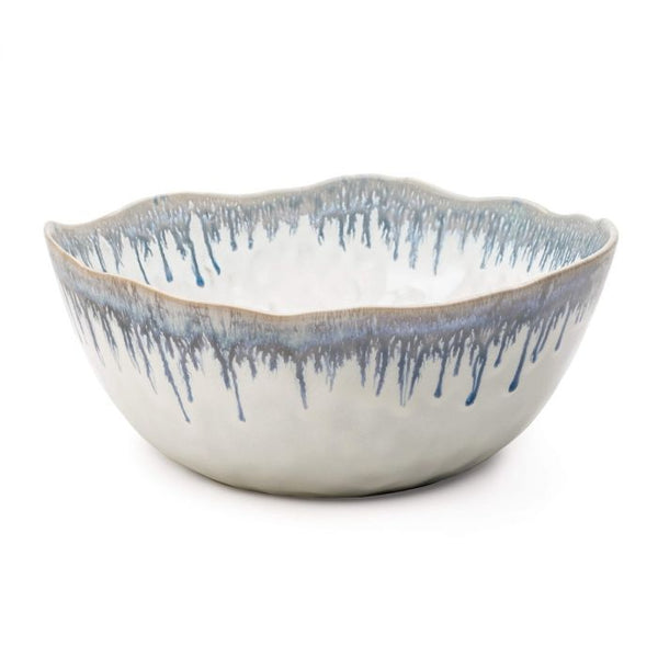 A Simon Pearce Burlington Pool Serving Bowl featuring a scalloped rim and an organic glaze with blue dripping patterns on the exterior.