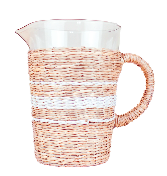 The Seagrass Wrapped Pitcher, White/Natural by Be Home is a classic pitcher with a transparent glass body and handle, adorned with pink and white stripes, wrapped in seagrass and equipped with a convenient pour spout.