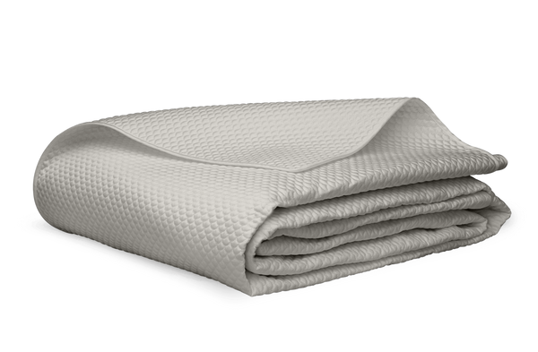 A folded silver Matouk Alba Bedding Collection Egyptian cotton sateen blanket on a white background.