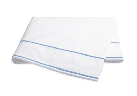 A folded white sheet with blue stripes along the edges, crafted from luxurious Luca cotton percale from the Matouk Ansonia Bedding Collection in Ocean by Matouk.