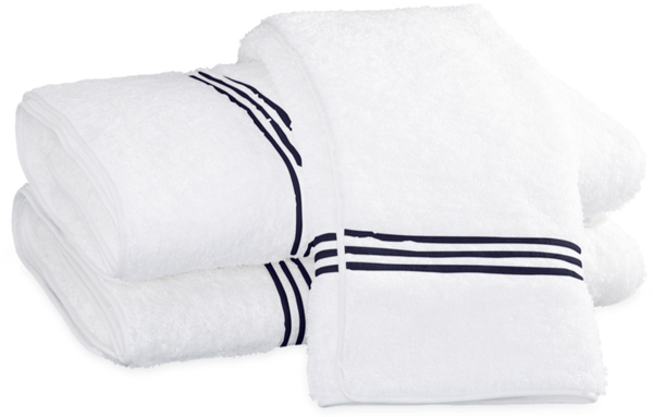 Three folded white luxury towels with navy blue stripe accents, crafted from Cairo long-staple cotton, stacked on top of each other—a true Matouk Bel Tempo Bath Collection - Navy trio.