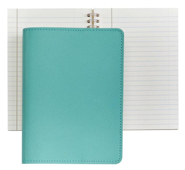 A closed Graphic Image Leather Wire Ring Notebook, Robins Egg Blue, 7”, placed on top of an open spiral-bound lined notebook, both against a plain white background. Perfect for journal writing with its premium paper quality.