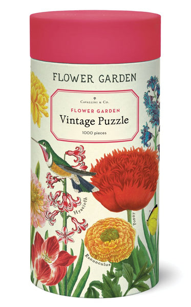 A cylindrical box labeled "Cavallini & Co. Flower Garden 1,000 Piece Puzzle" by Cavallini Papers and Co. contains a 1,000 piece puzzle featuring colorful flower illustrations and a hummingbird, inspired by the Cavallini archives.