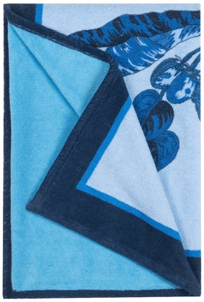 A folded Matouk Tallulah Palm Beach Towel in Prussian Blue, with a darker blue border and floral design, perfect as a summer essential.