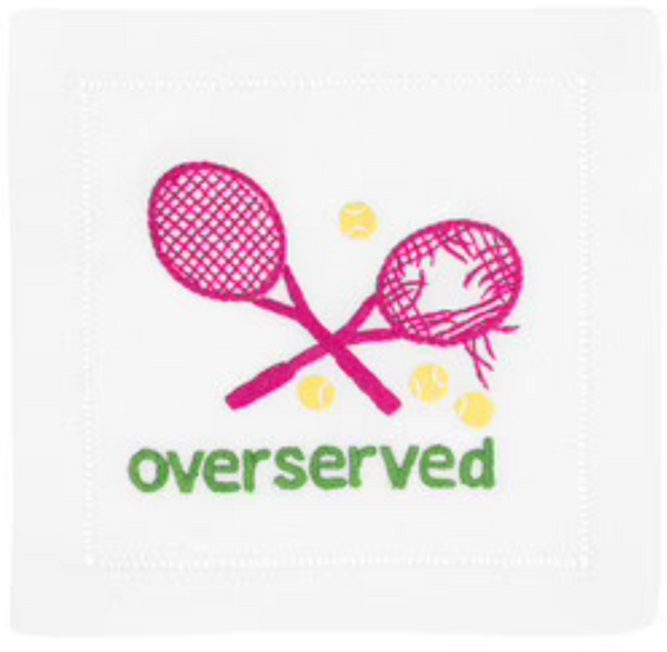 A linen napkin featuring embroidered imagery of two crossed pink tennis rackets, three yellow tennis balls, and the word "overserved" in green - August Morgan Cocktail Napkins Overserved Pink, Set of 4.