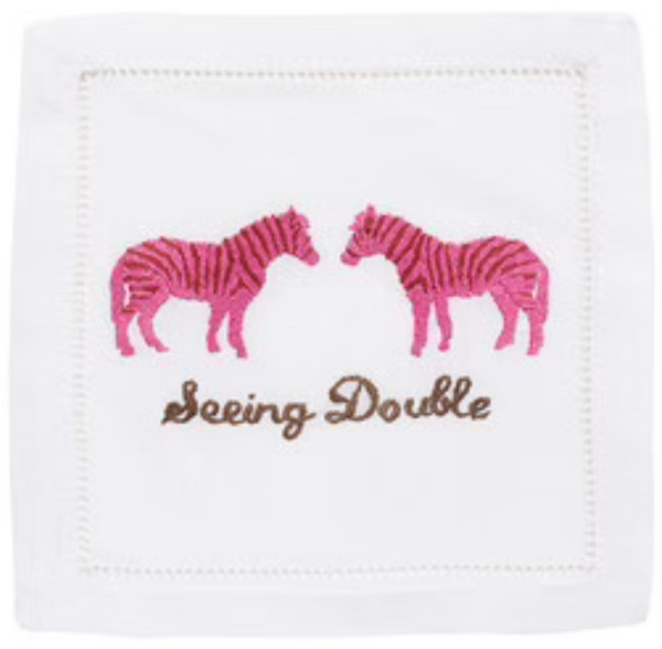 An elegant linen cloth with embroidered pink zebras facing each other above the text "Seeing Double" in brown stitching, featuring classic hemstitching, is the August Morgan Cocktail Napkins Seeing Double, Set of 4 by August Morgan.