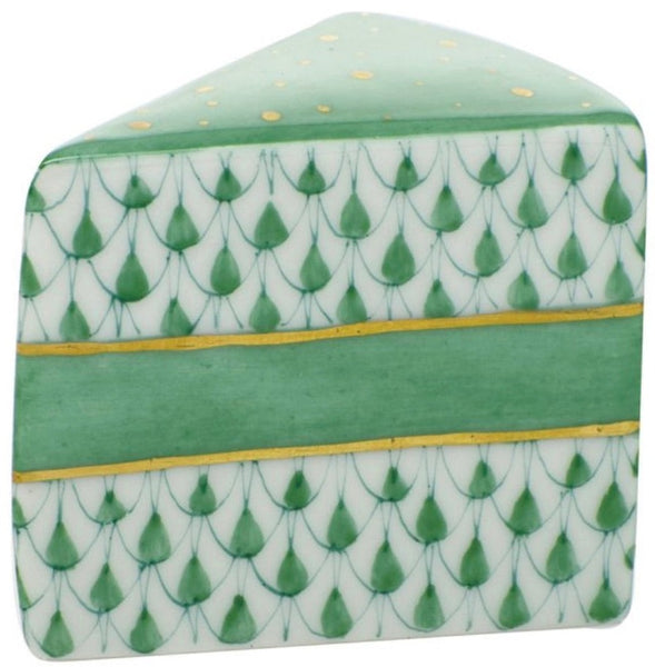 The Herend Slice of Cake, a decorative ceramic piece by Herend, is shaped like a slice of cake and features a geometric green and white pattern with gold accents, reminiscent of the brand's hand-painted designs.