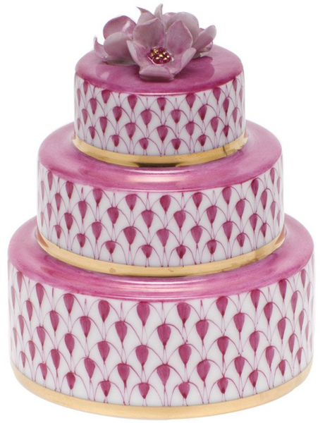 The Herend Wedding Cake by Herend is a three-tiered decorative box, featuring hand-painted designs with a pink floral pattern and a flower adorning the top.