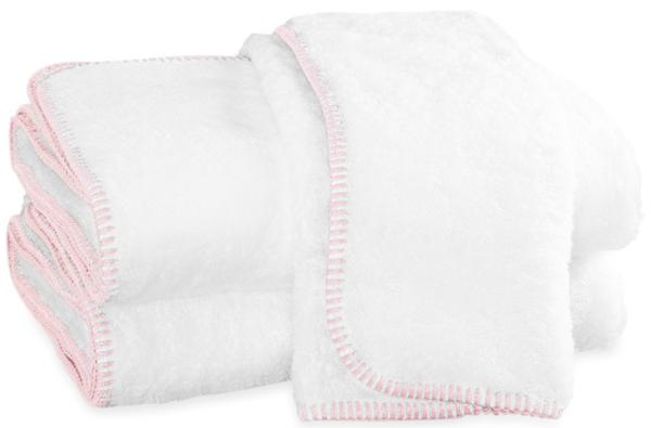 Two neatly folded white towels with pink-stitched edges, part of the Matouk Whipstitch Bath Collection - Pink and made from OEKO-TEX® certified long-staple cotton, placed next to each other on a white background.