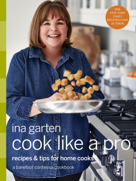 Cover of "Cook Like a Pro" by Penguin Random House, featuring cookbook author Ina Garten smiling in a kitchen as she flips food items in a frying pan. The cover proudly displays a "New York Times Bestselling Author" badge.