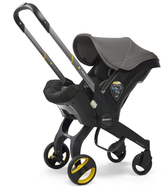 A side view of the Doona Car Seat and Stroller, featuring a black and gray design with an extended handle and yellow-accented wheels. This versatile travel system from Doona easily transitions between car seat and stroller for maximum convenience.