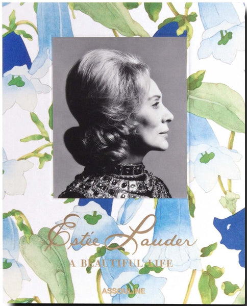 Black and white profile photograph of a woman with styled hair on the cover of "Estée Lauder: A Beautiful Life," a book by Assouline. The book, which resembles a personal album with its floral background, chronicles the journey of building her cosmetics empire.