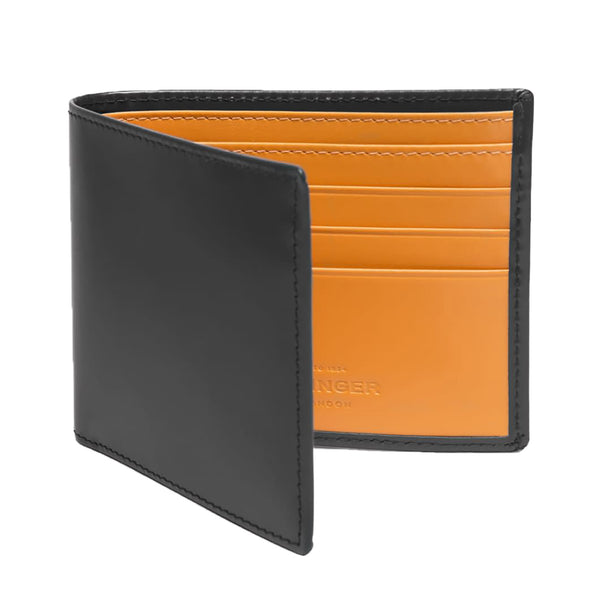 The Ettinger Bridle Billfold 6 Credit Card Wallet, crafted by Ettinger, is a black bifold leather wallet that opens to reveal its London Tan interior and multiple card slots, made from traditional English bridle leather.