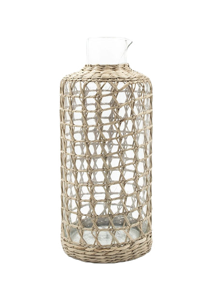 The Seagrass Cage Carafe by Be Home features a glass bottle with a narrow neck encased in a decorative woven seagrass wrapping.