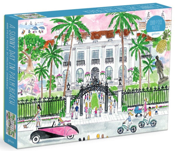 A Michael Storrings A Sunny Day in Palm Beach 1,000 Piece Puzzle box depicting an illustrated scene of a lively day at Palm Beach, with people engaged in various activities in front of an elegant building surrounded by palm trees.