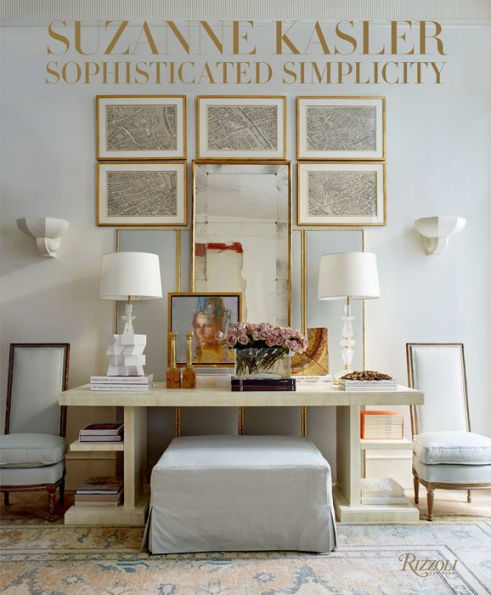 A stylish, light-colored living space featuring a large mirror, wall art, two table lamps, and a beige table with decor—perfect for family homes. The cover text reads "Suzanne Kasler: Sophisticated Simplicity" by Rizzoli.