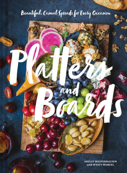 Cover of the book "Platters and Boards" by Shelly Westerhausen and Wyatt Worcel, from Common Ground, featuring a colorful spread of various fruits, cheeses, and nuts on a wooden board. The subtitle reads "Beautiful, Casual Spreads for Every Occasion," making it perfect for entertaining with ease.