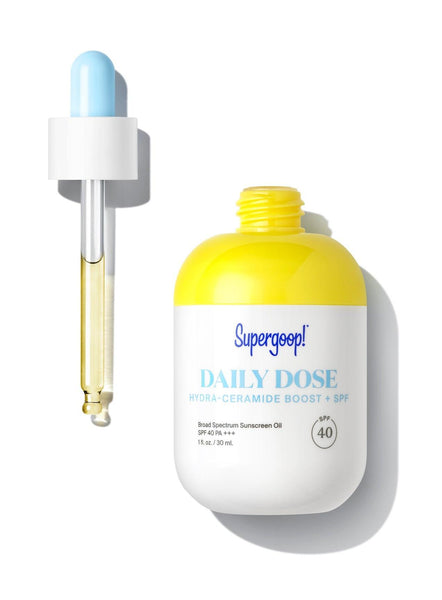 A bottle of Supergoop! Daily Dose Hydra-Ceramide Boost + SPF 40 Oil and a bottle of water for hydration and skin barrier protection.