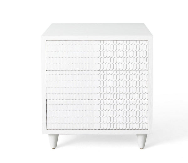 The Lance Bedside Table by Mr Brown is a white piece with three drawers, showcasing a textured wave design and finished in smooth white gesso. Standing at 26.5 inches high, it is ideal for compact spaces and is set against a plain background to accentuate its elegant proportions.