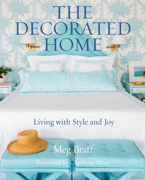 Cover of the book "The Decorated Home" by Common Ground, featuring a neatly made bed with light blue and white bedding, a straw hat on an ottoman, and a tropical wallpaper background. An ode to gracious living by an acclaimed interior designer that showcases stylish bedrooms.